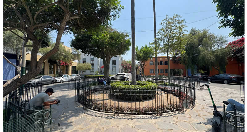 rechteckige Platzanlage mit Grünflächen, Metallbänken und klassischen Laternen